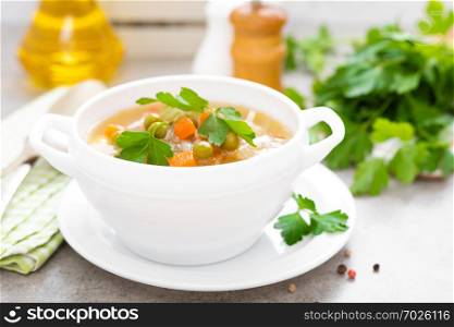 Summer light vegetarian vegetable soup with carrot, potato, cabbage and grean peas on white background. Diet healthy and tasty lunch. Baby food