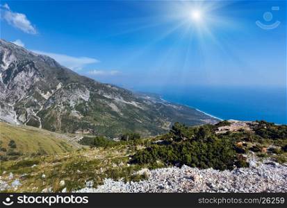 Summer Llogara pass sunshiny view with road, herd of goats on slope and sea water surface (Albania)