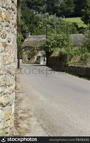 Summer looking towards thatched cottage. The main street in Loders near Bridport, England, United Kingdom.