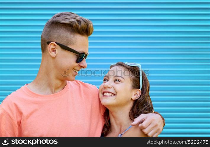summer, love and people concept - happy smiling teenage couple hugging over blue background. happy teenage couple hugging over blue background