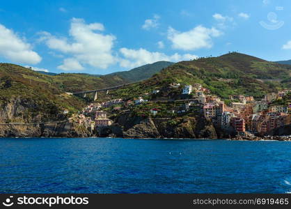 Summer Manarola view from excursion ship. One of five famous villages of Cinque Terre National Park in Liguria, Italy, suspended between Ligurian sea and land on sheer cliffs. People unrecognizable.