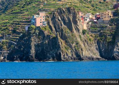 Summer Manarola view from excursion ship. One of five famous villages of Cinque Terre National Park in Liguria, Italy, suspended between sea and land on sheer cliffs.People unrecognizable.