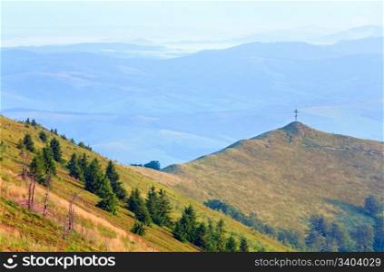 summer misty mountain landscape with christian cross on top (Ukraine, Carpathian Mountains)