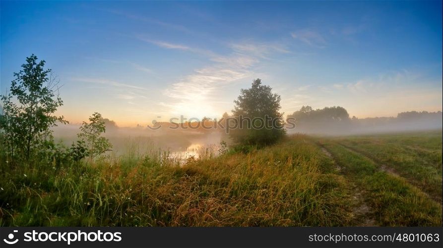 Summer misty sunrise on the river. Foggy river in the morning. Misty morning panorama.
