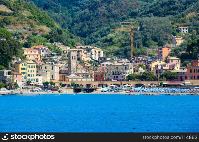 Summer Monterosso view from excursion ship. One of five famous villages of Cinque Terre National Park in Liguria, Italy, suspended between sea and land on sheer cliffs. People unrecognizable.