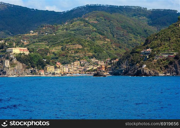 Summer Monterosso view from excursion ship. One of five famous villages of Cinque Terre National Park in Liguria, Italy, suspended between sea and land on sheer cliffs. People unrecognizable.