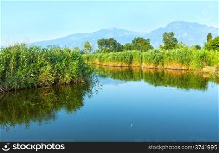 Summer morning misty mountain landscape with water surface in front (Greece).