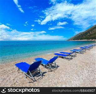 Summer morning pebbly beach with blue sky and sunbeds on beach (Albania). Two shots stitch image.