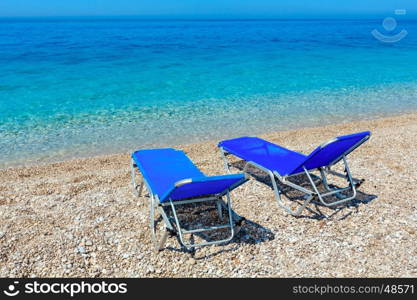 Summer morning pebbly beach with sunbeds (Albania).