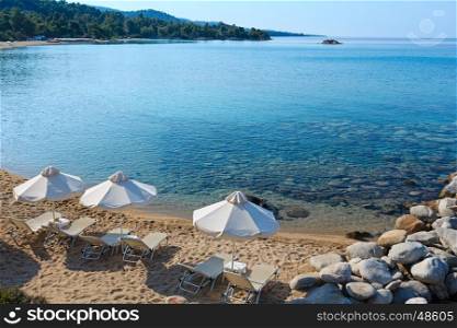 Summer morning sandy beach with sunbeds and sunshades (Sithonia, Chalkidiki, Greece).