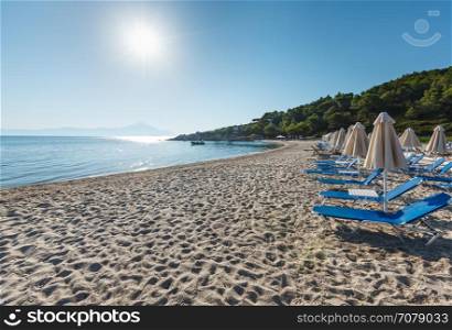 Summer morning sandy Platanitsi beach with sunbeds and sunshades (Chalkidiki, Greece).