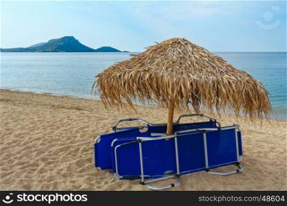 Summer morning sandy Tristinika beach with sunbeds and sunshade (Sithonia, Chalkidiki, Greece).