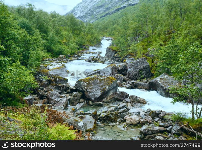 Summer mountain cloudy view with river on slope (Norway).