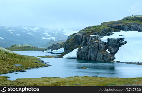 Summer mountain misty landscape with lake and snow (Norway, Aurlandsfjellet).