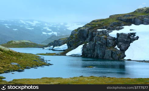 Summer mountain misty landscape with lake and snow (Norway, Aurlandsfjellet).