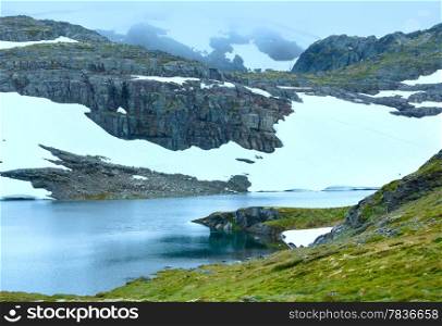 Summer mountain misty landscape with lake and snow (Norway, Aurlandsfjellet).