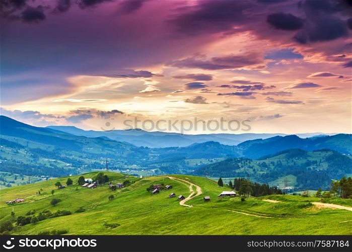 Summer mountain rural landscape, awesome evening sunset view on village and meadow. Colorful evening in mountain valley. Beauty of nature background. Europe travel, Carpathians, Ukraine.