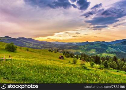 Summer mountain rural landscape. Sunset view on village meadow and lonely hut. Colorful evening in mountain valley. Beauty of nature background. Europe travel, Carpathians, Ukraine