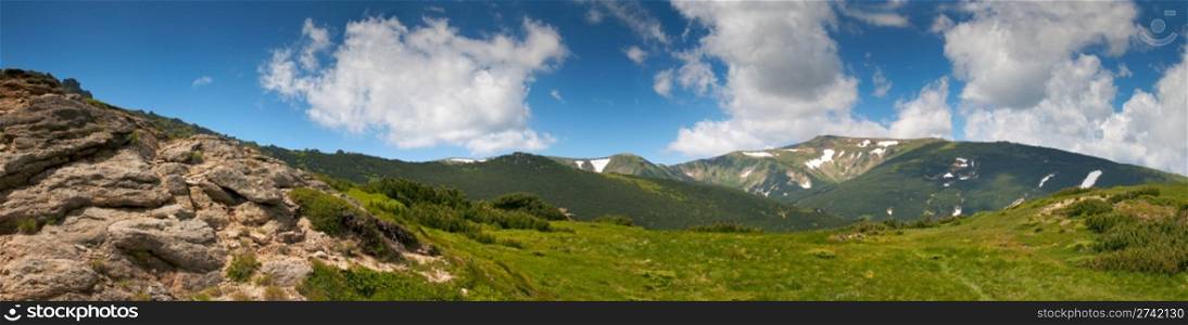 Summer mountain view with snow and big stones on mountainside. Four shots stitch image.