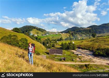 Summer mountain village landscape and woman with tripod in front