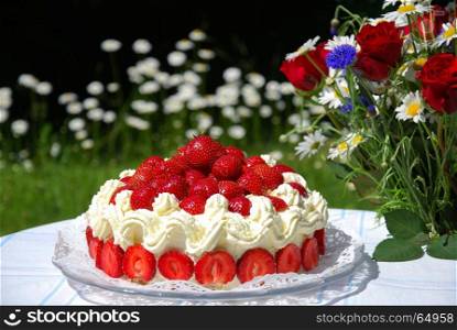 Summer objects in a garden - strawberry cake and a bouquet with summer flowers