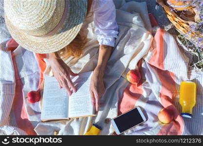 Summer - picnic by the sea. basket for a picnic with with buns, apples and juice. girl on a picnic lies and reads a book