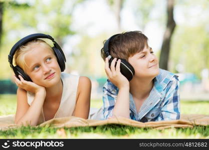 Summer picnic in park. Cute boy and girl in summer park listening to music