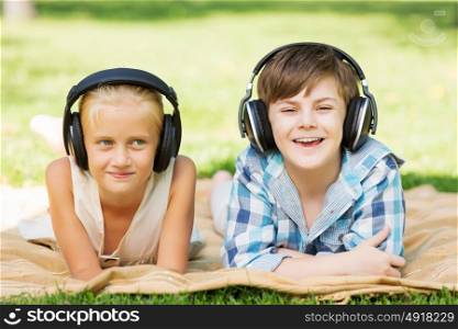Summer picnic in park. Cute boy and girl in summer park listening to music
