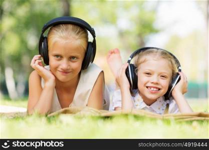 Summer picnic in park. Cute girls in summer park listening to music