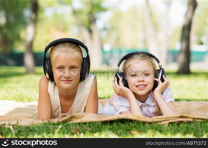 Summer picnic in park. Cute girls in summer park listening to music
