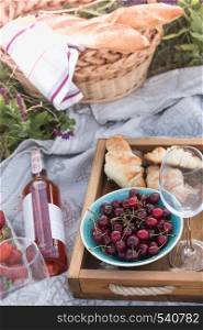 Summer - picnic in the meadow. Cheese brie, baguette, strawberry, cherry, wine, croissants and basket