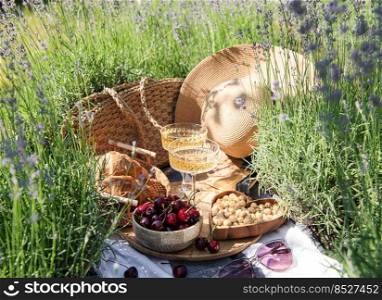 Summer picnic on a lavender field with ch&agne glasses and cherry berries