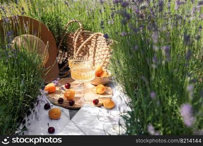 Summer picnic on a lavender field with ch&agne glasses, apricots and cherry berries