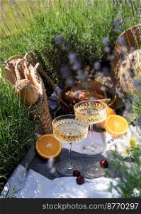 Summer picnic on a lavender field with champagne glasses and fruits