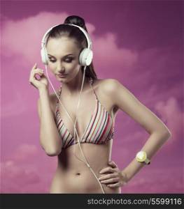 summer portrait of sexy girl with trendy bikini and wrist watch listening music with headphones