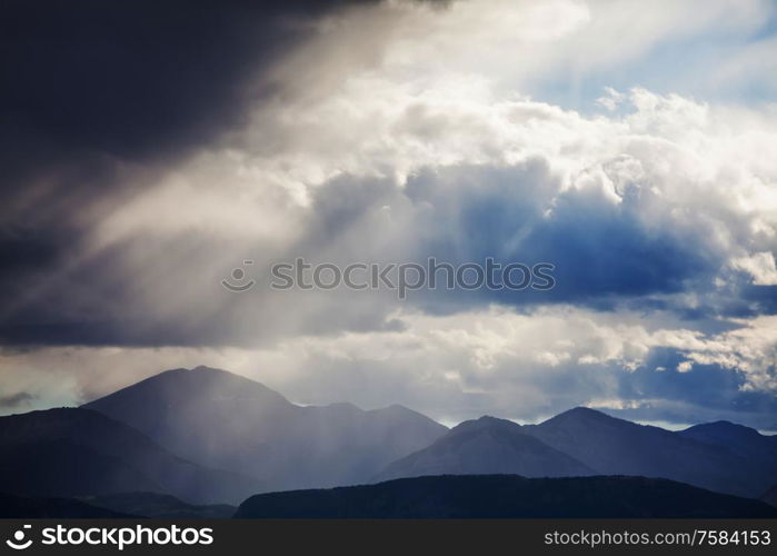 Summer rain in the mountains. Dramatic clouds and mountains silhouette.