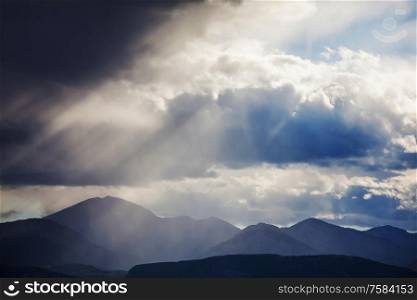Summer rain in the mountains. Dramatic clouds and mountains silhouette.