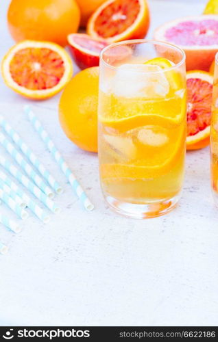 Summer refreshing citrus drinks in glasse with ice on white table with copy space. Summer citrus drinks