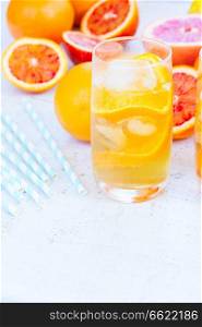 Summer refreshing citrus drinks in glasse with ice on white table with copy space. Summer citrus drinks