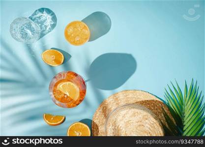 Summer refreshing cocktail aperol spritz with orange and palm leaves on a blue background with shadows, top view. Summer refreshing cocktail