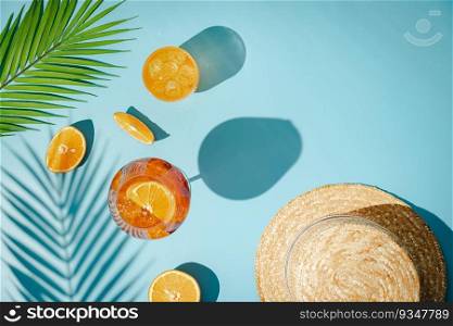 Summer refreshing cocktail aperol spritz with orange and palm leaves on a blue background with shadows, top view. Summer refreshing cocktail