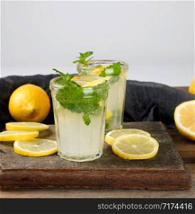 summer refreshing drink lemonade with lemons, mint leaves in a glass, next to the ingredients for making a cocktail