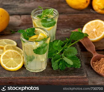 summer refreshing drink lemonade with lemons, mint leaves in a glass, next to the ingredients for making a cocktail