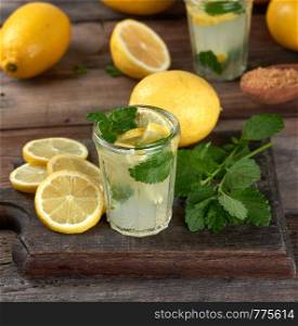 summer refreshing drink lemonade with lemons, mint leaves in a glass, next to the ingredients for making a cocktail