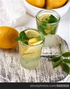 summer refreshing drink lemonade with lemons, mint leaves, lime in a glass , next to the ingredients for making a cocktail, top view