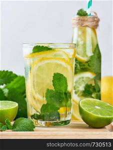 summer refreshing drink lemonade with lemons, mint leaves, lime in a glass , next to the ingredients for making a cocktail
