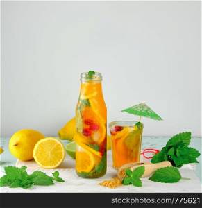 summer refreshing drink lemonade with lemons, mint leaves, lime in a glass , next to the ingredients for making a cocktail