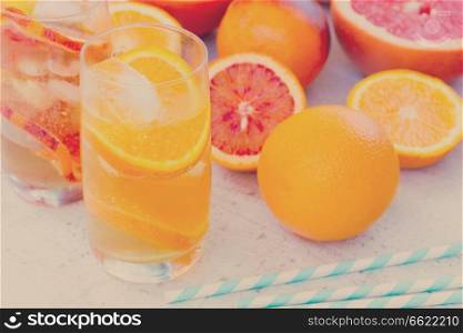 Summer refreshing orange citrus drinks with ice on white wooden table, retro toned. Summer citrus drinks