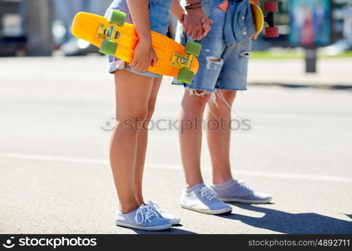 summer, relations, extreme sport and people concept - close up of happy teenage couple with short modern cruiser skateboards on city street