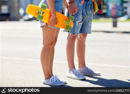 summer, relations, extreme sport and people concept - close up of happy teenage couple with short modern cruiser skateboards on city street